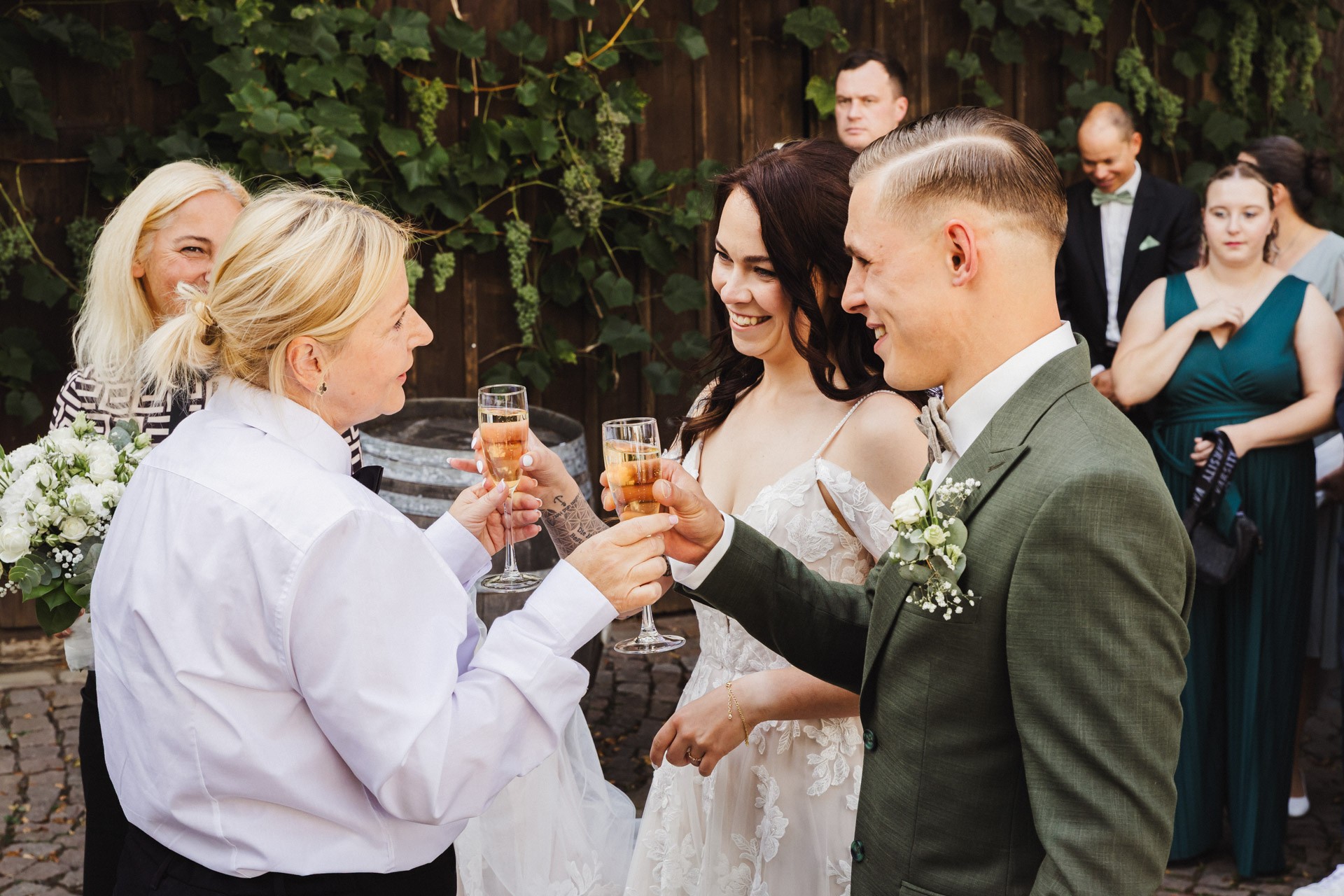 Lachende Gäste und Anschneiden der Torte im Garten der Hochzeitskapelle Callenberg (Sachsen).