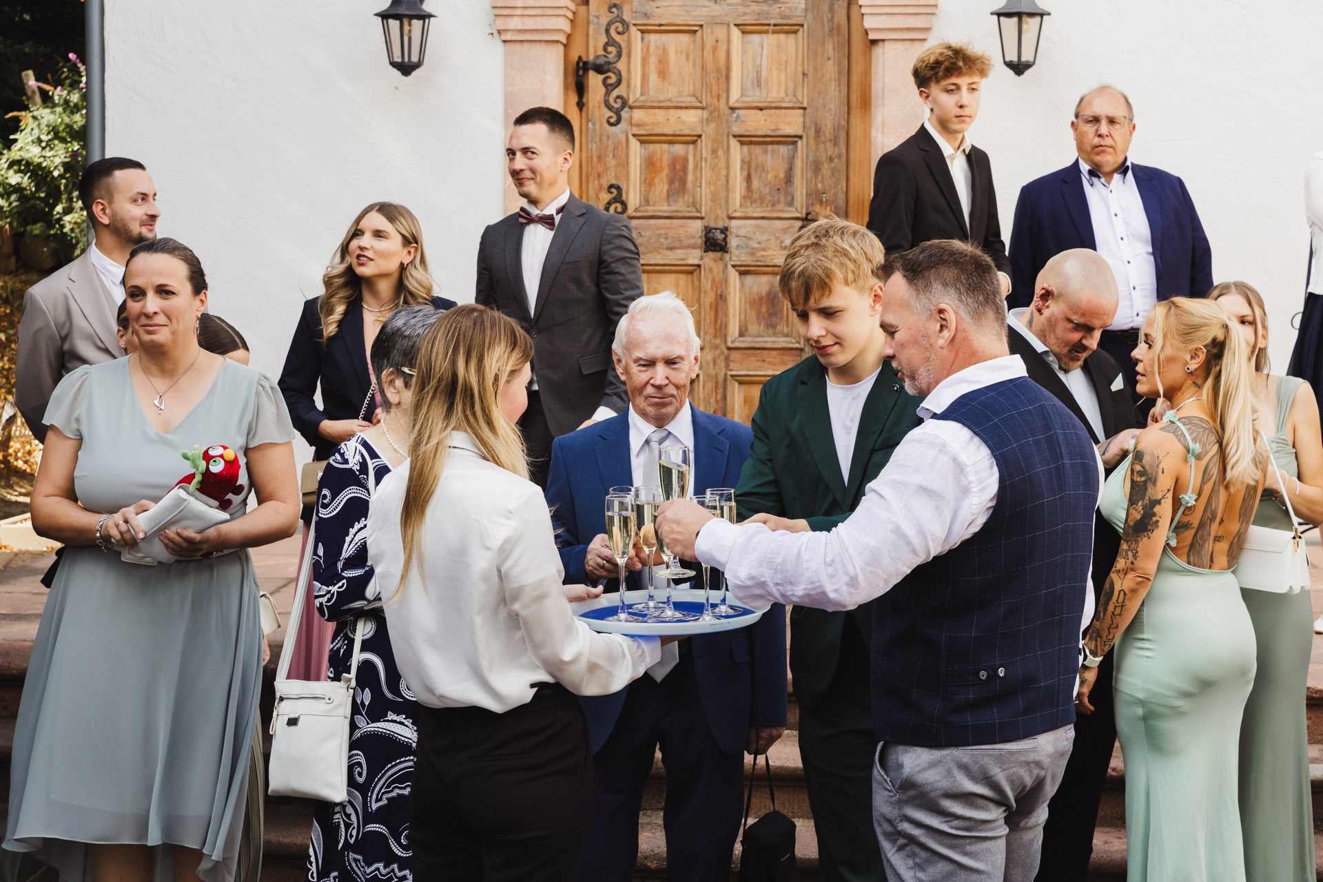 Lachende Gäste und Anschneiden der Torte im Garten der Hochzeitskapelle Callenberg (Sachsen).