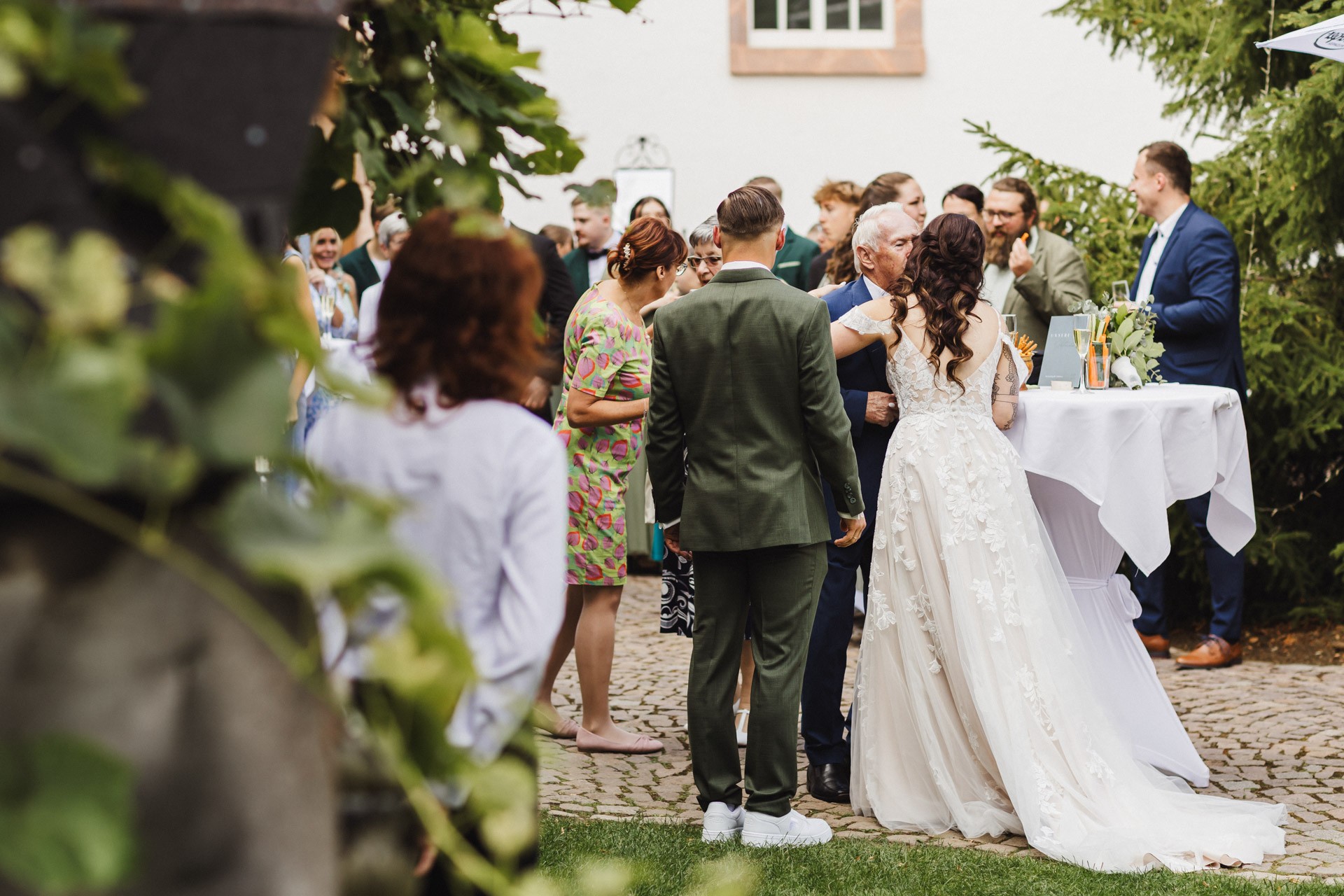 Lachende Gäste und Anschneiden der Torte im Garten der Hochzeitskapelle Callenberg (Sachsen).