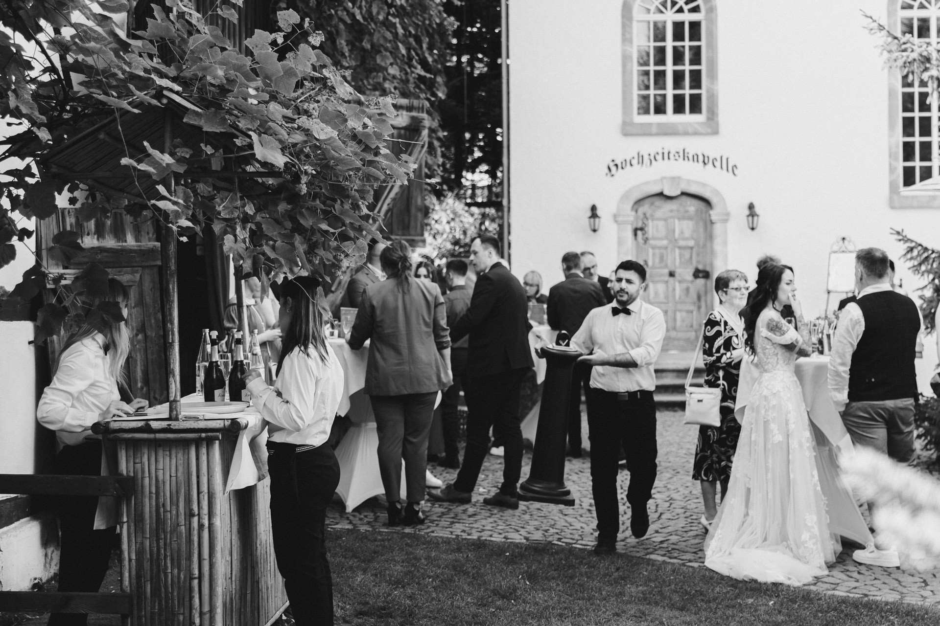 Lachende Gäste und Anschneiden der Torte im Garten der Hochzeitskapelle Callenberg (Sachsen).