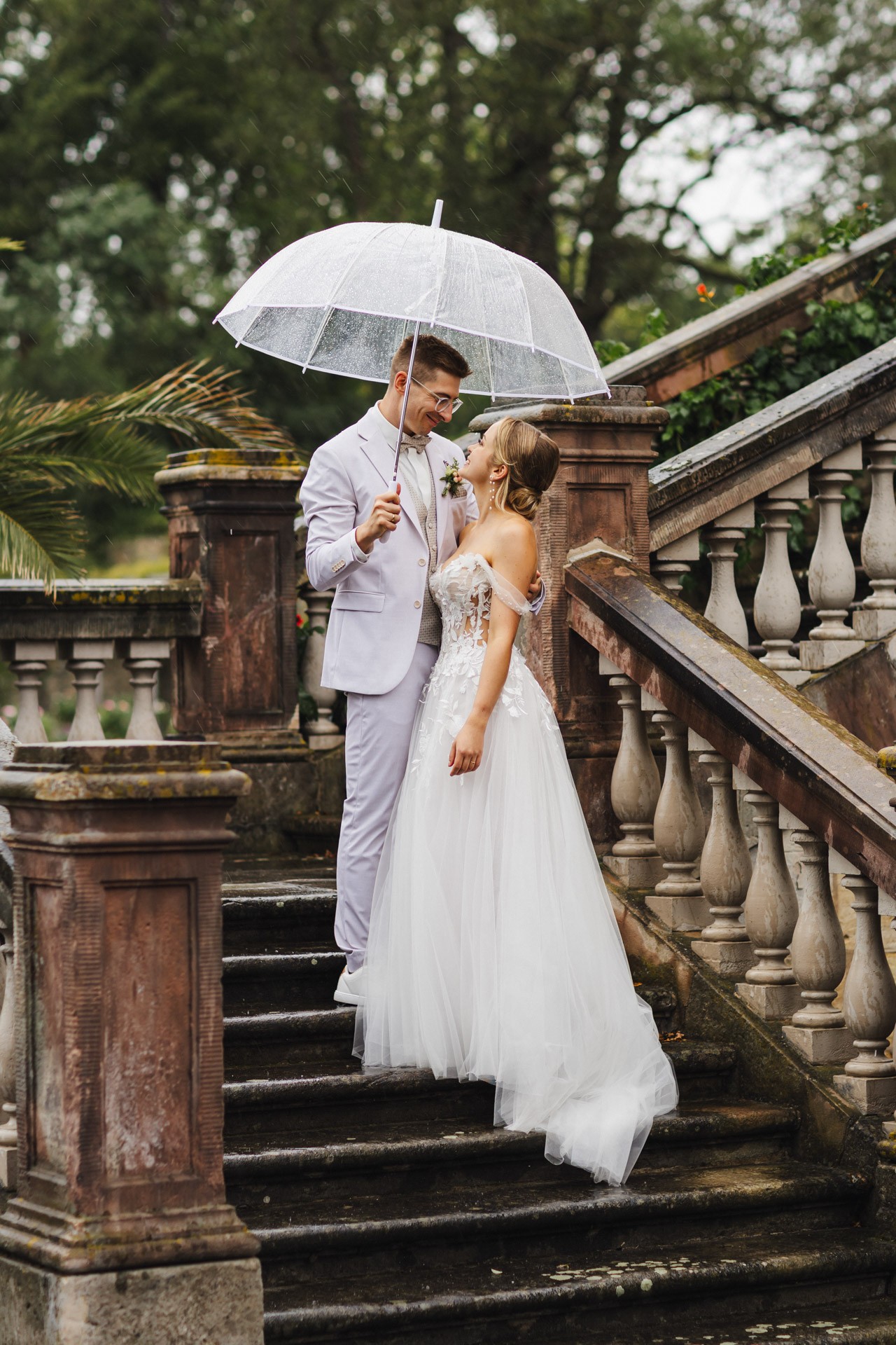 Brautpaar lacht entspannt beim Paarshooting im Schlosspark Ettersburg bei Regen. Danach elegante Paarfotos und romantische Schleierportraits im Weißen Saal.