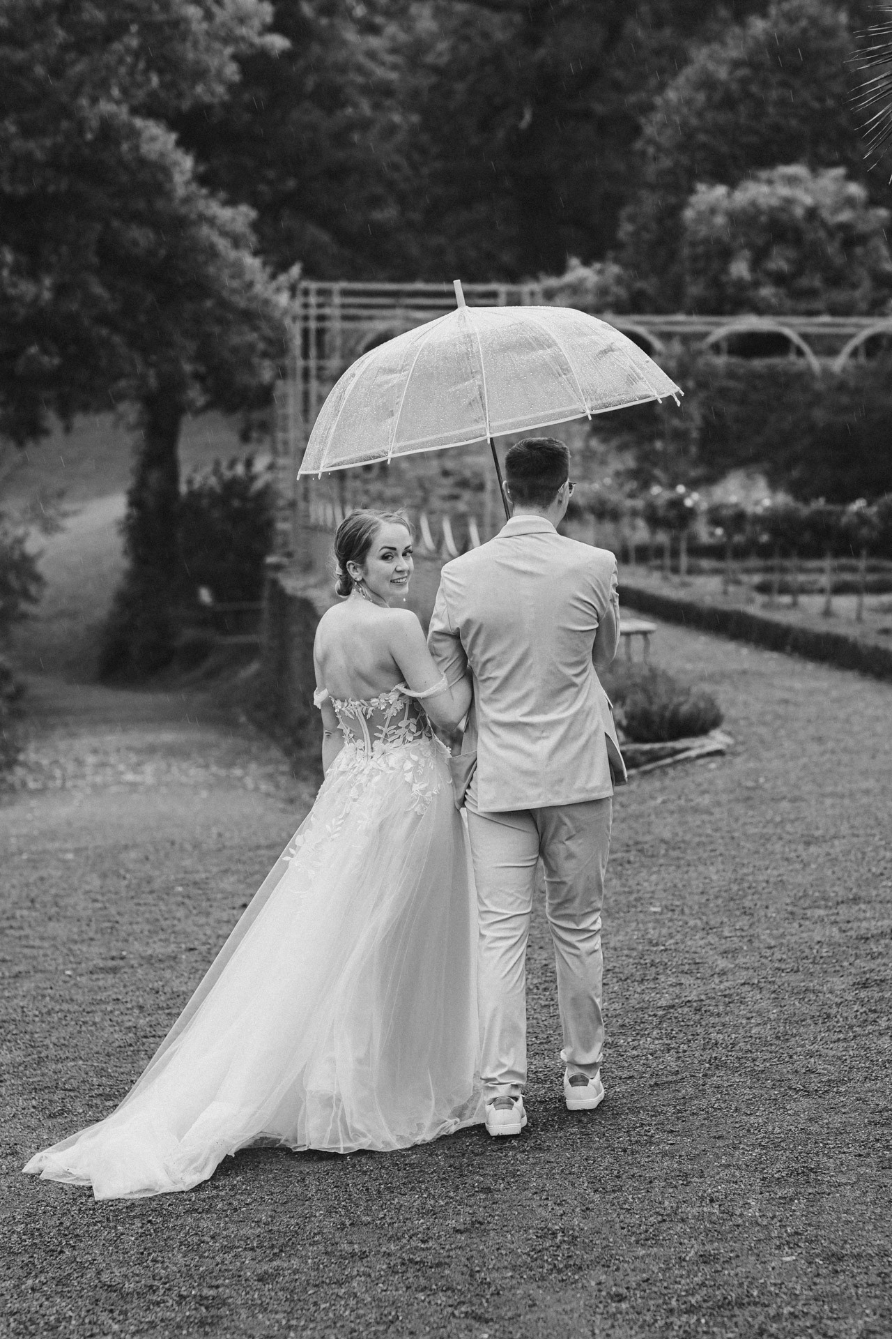 Brautpaar lacht entspannt beim Paarshooting im Schlosspark Ettersburg bei Regen. Danach elegante Paarfotos und romantische Schleierportraits im Weißen Saal.