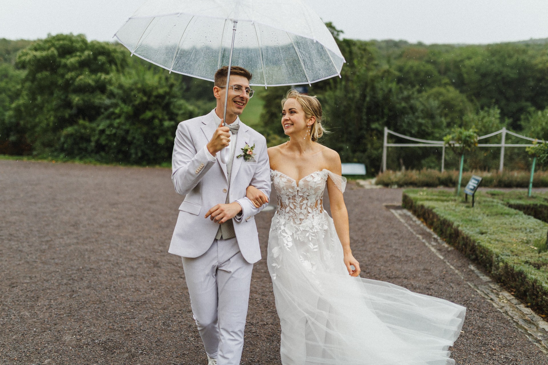 Brautpaar lacht entspannt beim Paarshooting im Schlosspark Ettersburg bei Regen. Danach elegante Paarfotos und romantische Schleierportraits im Weißen Saal.